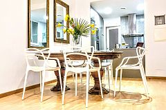 A vintage mahogany table is a luxury for six people, who may gracefully sit on six Curve dining chairs by Kartell at the Parsifal with balcony luxury apartment for short term rentals in Barcelona